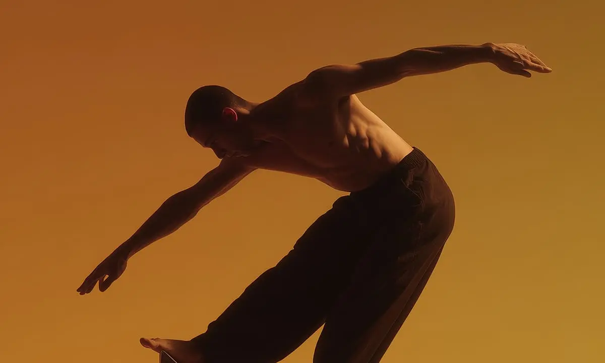 A shirtless man balancing on the top of a structure.